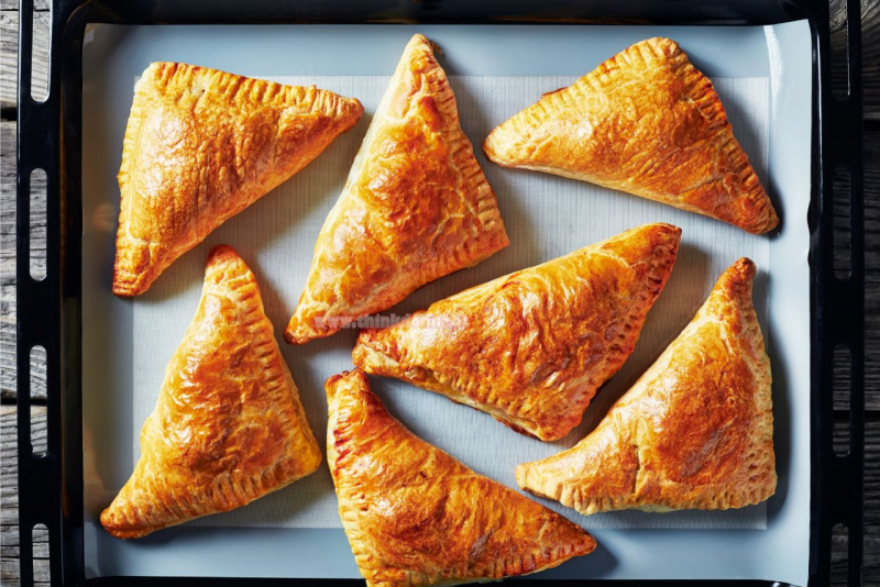 placca del forno coperta di carta forno apple turnover sfogliatelle dorate ripiene di mele