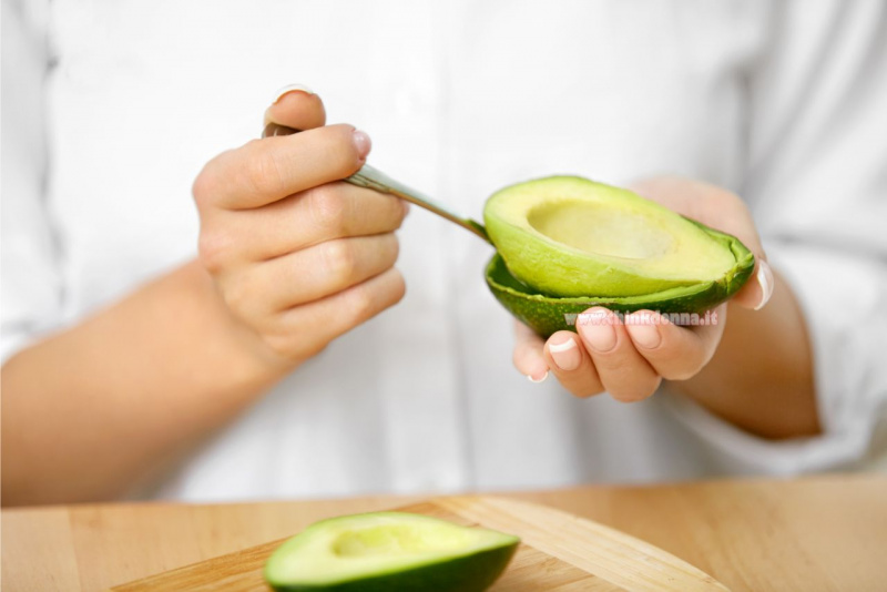 polpa avocado rimossa con cucchiaio mani tavolo legno