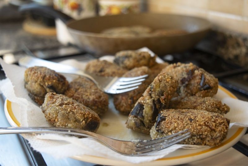 preparazione polpette di melanzane e patate padella frittura forchette piatto carta assorbente