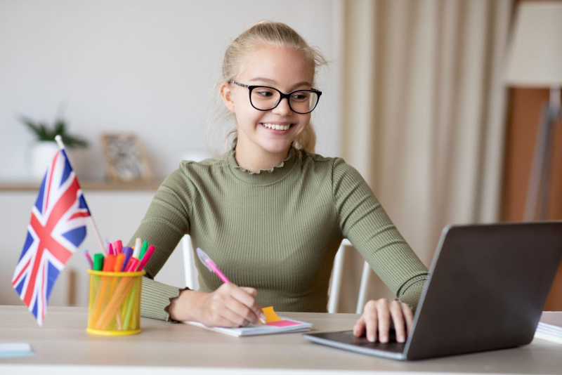 giovane bella bambina capelli biondi sorriso occhiali studia laptop libri