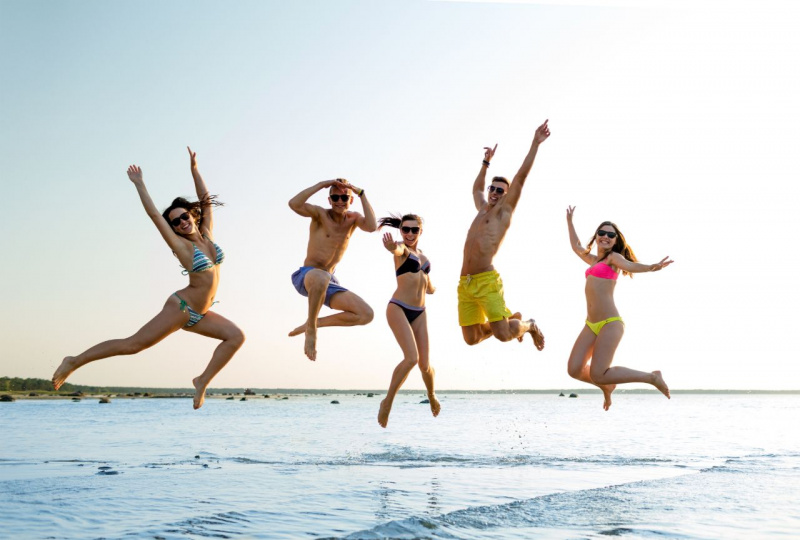 divertimento movimento estate amici ragazzi ragazze saltano spiaggia sabbia mare