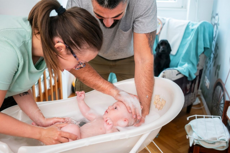 uomo donna genitori sorreggono bambino neonato in acqua per il bagno