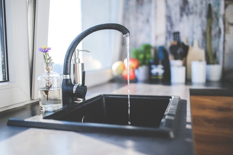 lavello nero cucina rubinetto acqua aperta finestra luminosa vasetto fiore viola