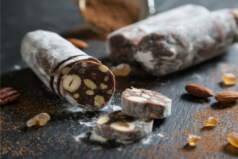 fetta salame di cioccolato nocciole mandorla zucchero a velo tavolo legno cacao amaro