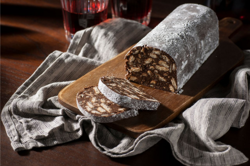 tagliere di legno con dolce salame di cioccolato strofinaccio bicchiere vino rosso