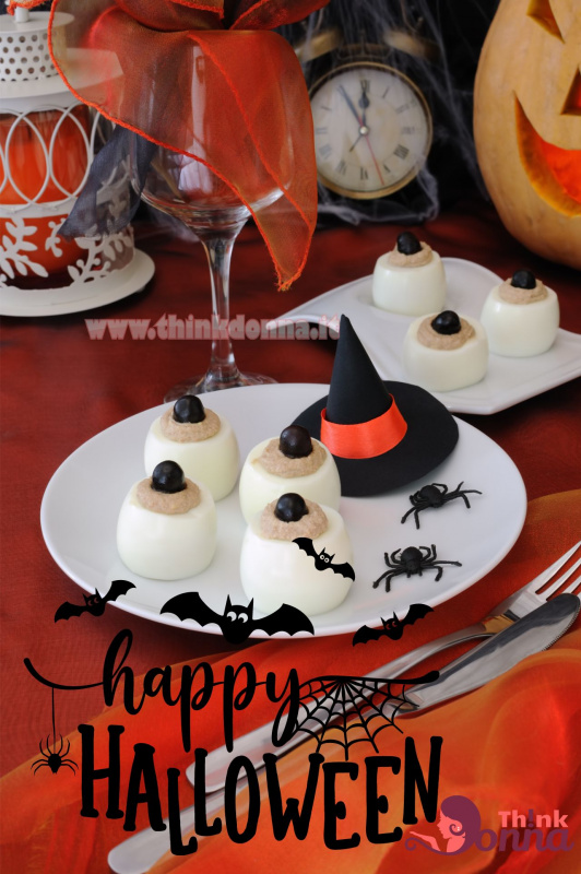 antipasto Halloween uova ripieni di salsa tonnata olive nere a forma di occhi su piatto bianco cappello di strega ragni