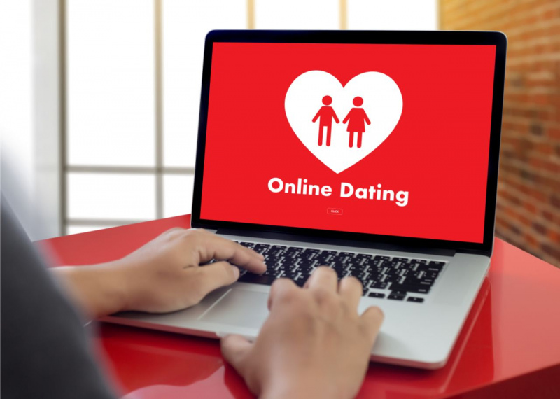 schermo laptop fondo rosso cuore bianco sagome uomo donna concetto siti incontri online mani uomo tastiera notebook