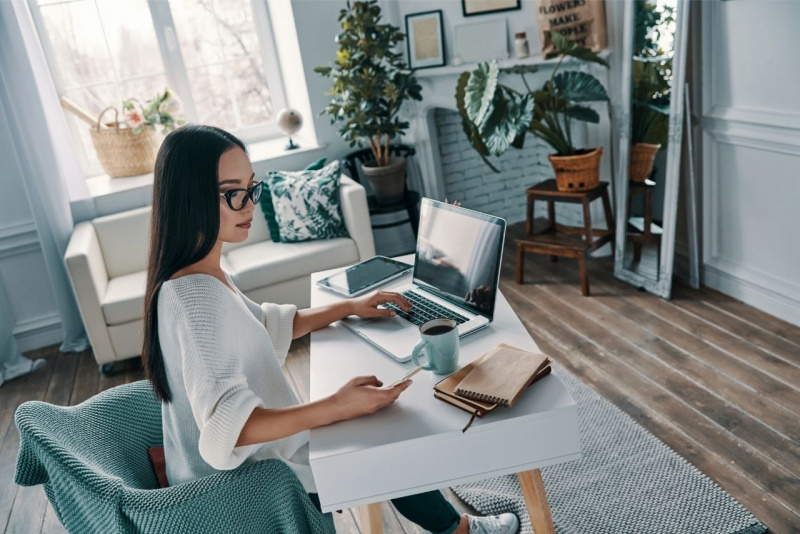 lavorare da casa online soggiorno divano finestra luce bella donna occhiali cellulare