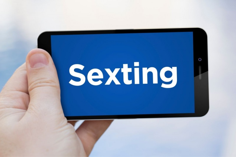smartphone in mano con scritta sexting