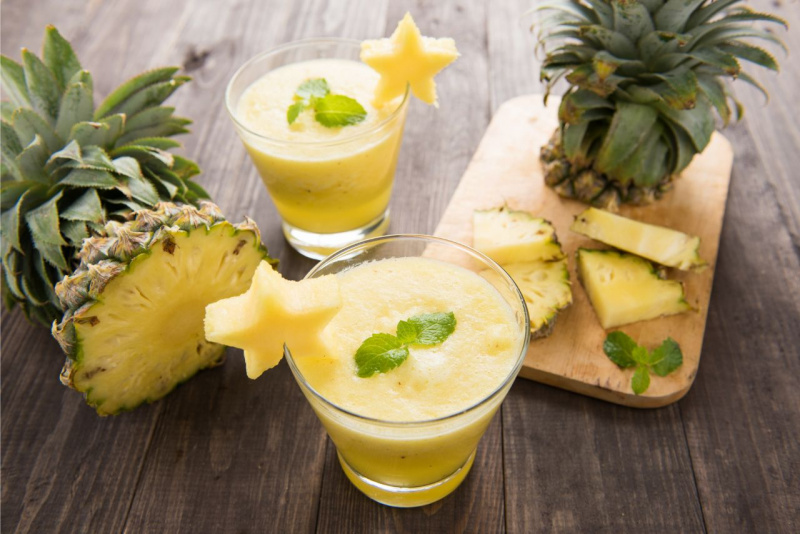 due bicchieri con frullato ananas fresco su tavolo legno