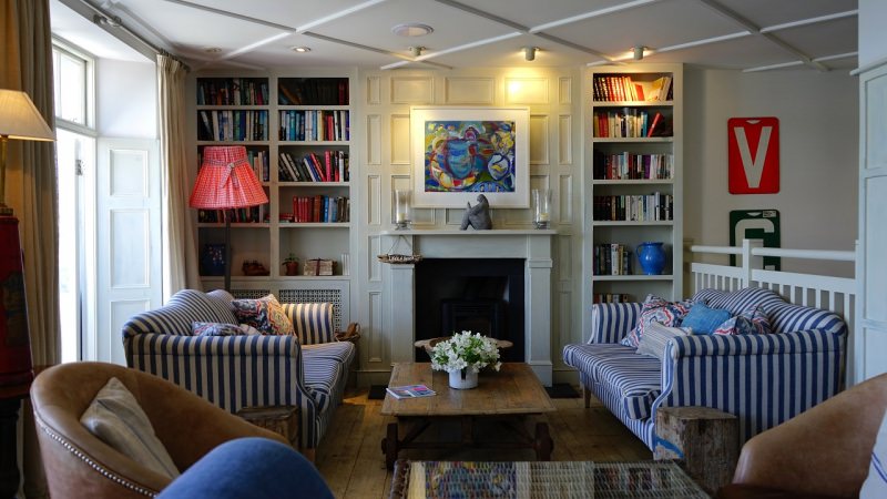 soggiorno di casa colorato moderno mix libreria libri divani righe camino fiori