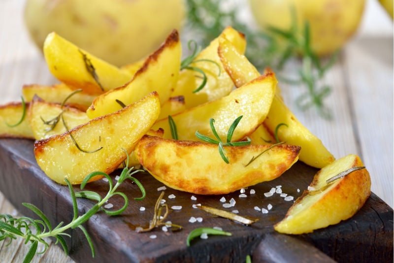 spicchi di patate arrosto rosmarino su tagliere legno