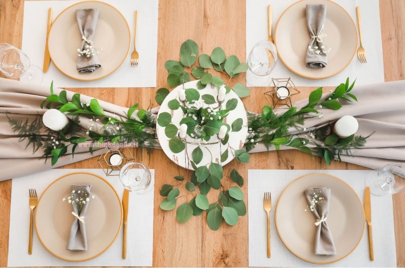 posto tavola apparecchiata centrotavola piatto con candelabro rami foglie verdi runner 