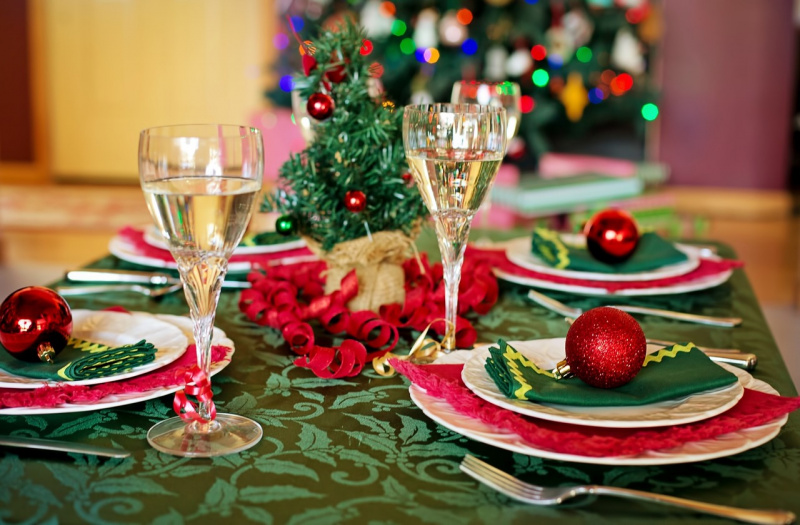 tavola apparecchiata festa natalizia tovaglia verde decorazioni rosse calici piatti