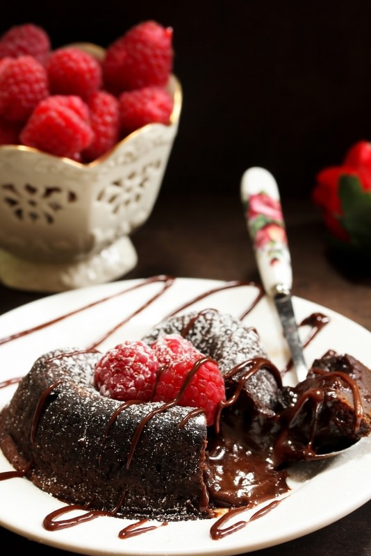 tortino al cioccolato dal cuore morbido cremoso dolce ciotola lamponi cucchiaio zucchero a velo