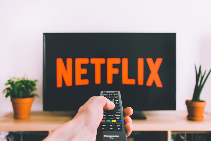 mano uomo telecomando TV Netflix soggiorno piante arredamento