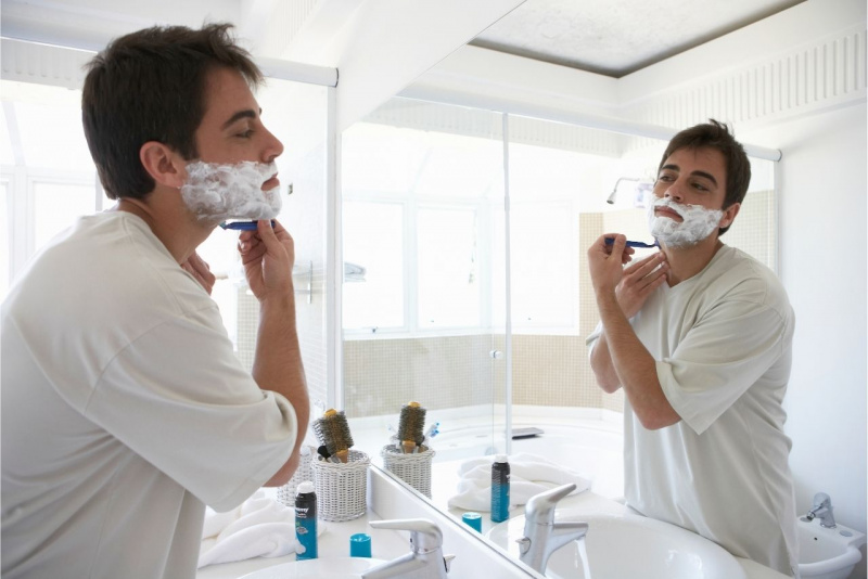 uomo si fa barba davanti specchio bagno