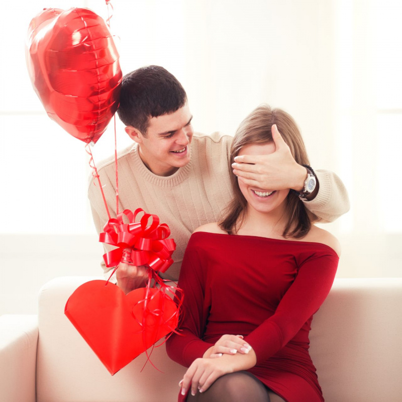 giovane innamorato chiude gli occhi della ragazza con la mano per farle sorpresa san valentino palloncini regalo forma di cuore