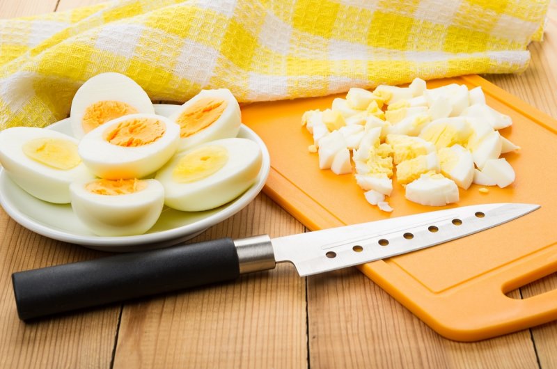 uova sode tagliate a pezzi coltello tagliere asciugapiatti cotone quadretti bianco giallo