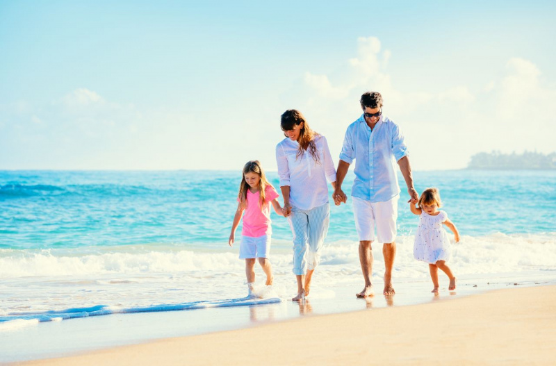 uomo papà donna mamma passeggiano riva mare tenendo per mano le figlie piccole