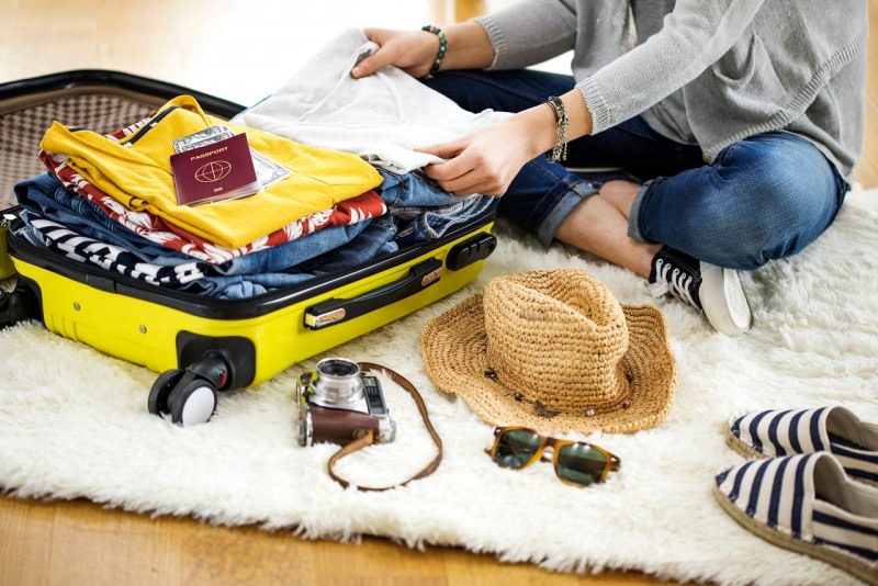 preparazione valigia trolley giallo passaporto vacanza estate