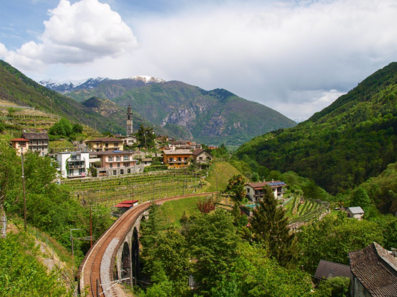 Val Vigezzo, villaggio Intragna nuvole cielo azzurro montagne neve campanile paesaggio