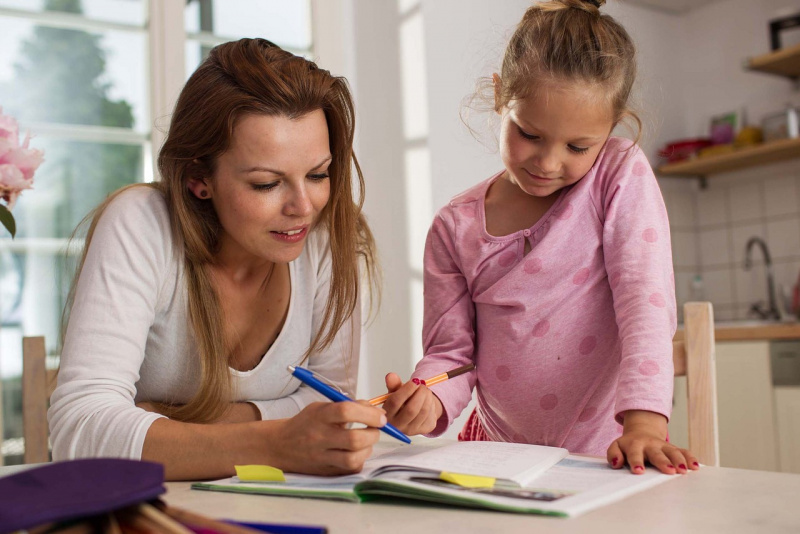 giovane mamma aiuta la figlia bambina a fare i compiti vacanze