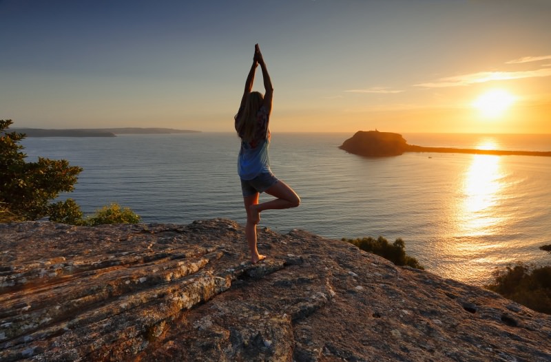 donna fa yoga davanti al mare al sorgere del sole