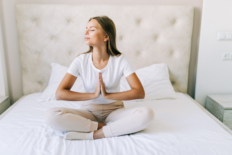 bella donna seduta sul letto posizione yoga meditazione